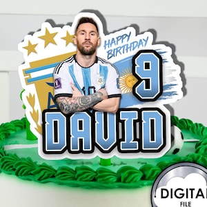 May include: A blue and white cake topper featuring a soccer player, the number 9, and the name "DAVID". The topper also includes the text "Happy Birthday" and a soccer ball.