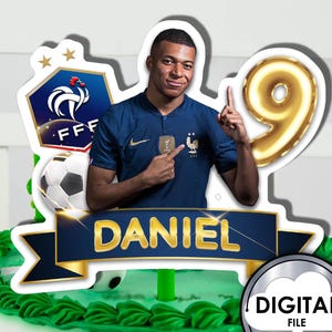 Puede incluir: Un adorno para pastel azul y dorado con un jugador de fútbol con un balón de fútbol, un logotipo de fútbol y el nombre "DANIEL". El adorno está diseñado para un pastel de cumpleaños.