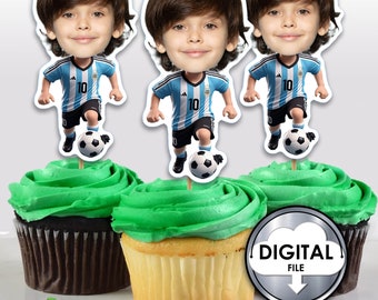 May include: Three cupcake toppers featuring a cartoon boy wearing a blue and white soccer jersey with the number 10 on it. The boy is kicking a soccer ball. The toppers are on top of cupcakes with green frosting.