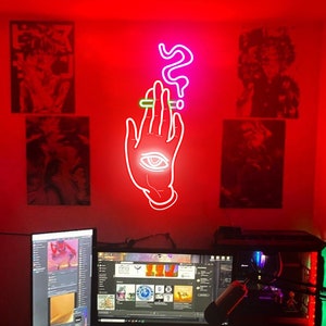 May include: A red room with a computer setup and neon signs on the wall. The neon signs are a hand with an eye and a question mark. The computer has three monitors, a keyboard, and a mouse.