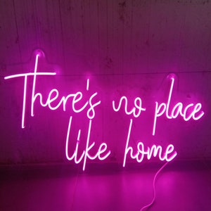 May include: Pink neon sign with the text "There's no place like home".
