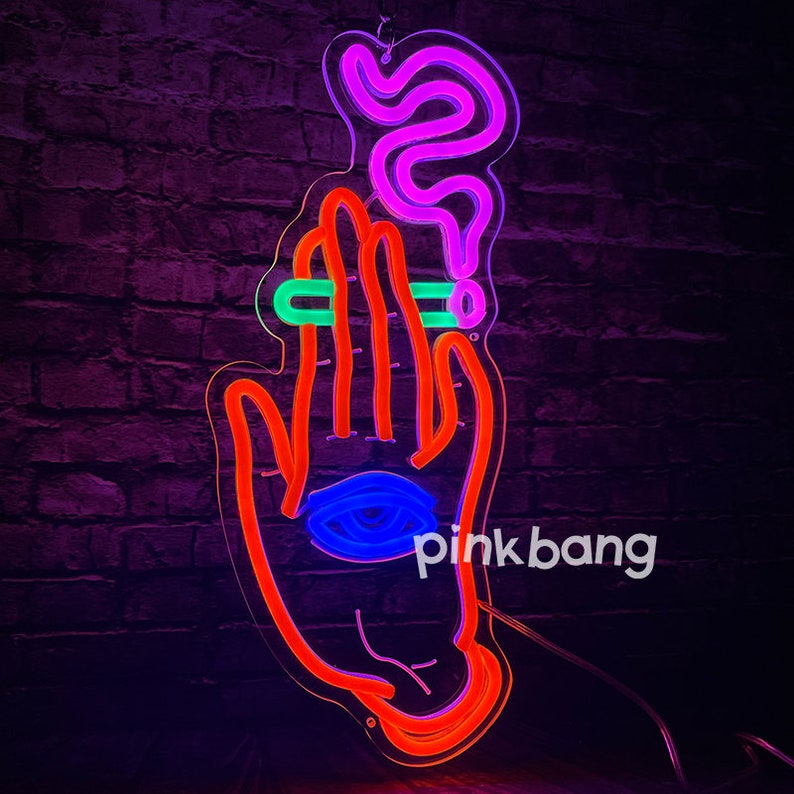 May include: Neon sign depicting a hand holding a cigarette with smoke rising above it. The hand has an eye in the palm. The sign is lit in red, blue, green, and purple neon colors. The text "pinkbang" is visible in the lower right corner.