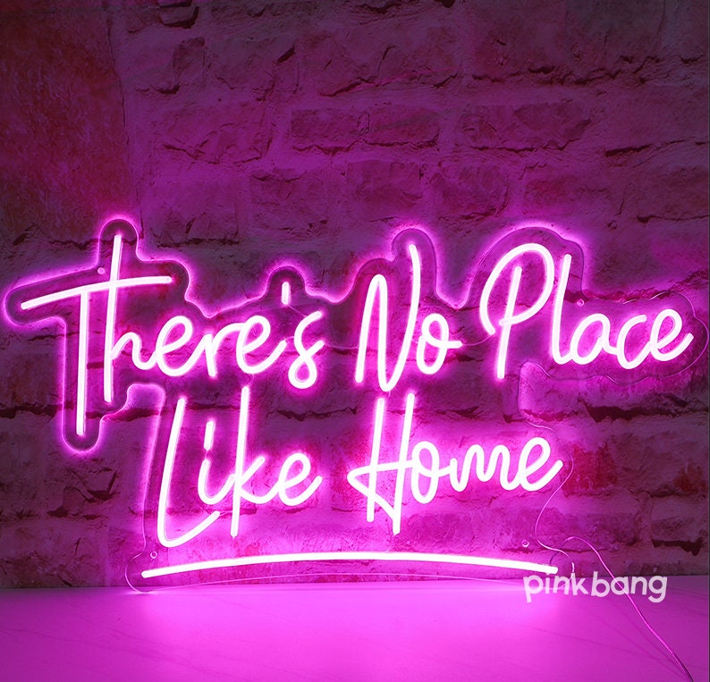 May include: Pink neon sign with the text "There's No Place Like Home".
