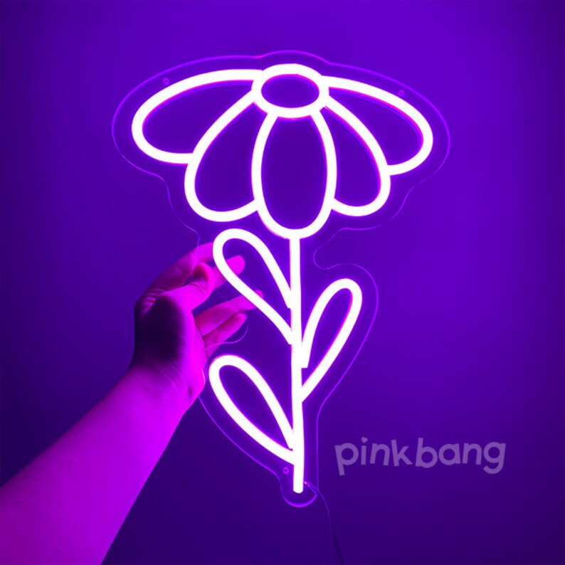 May include: White neon sign shaped like a flower with a stem and leaves. The sign is lit up in a bright purple color.