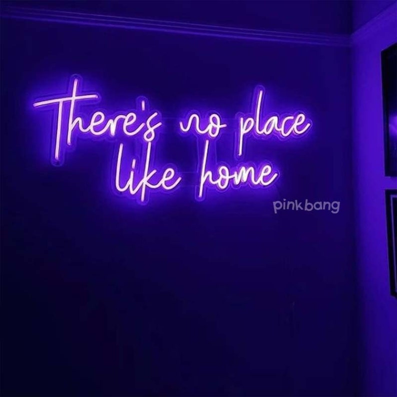 May include: Purple neon sign with the text "There's no place like home" on a dark purple wall.