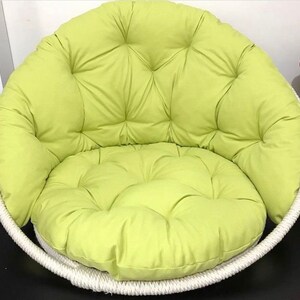 May include: A lime green padded cushion chair with a white rope frame. The chair has a round shape and a deep seat.