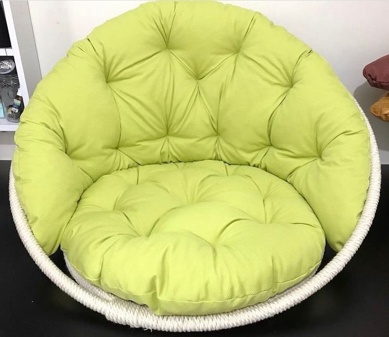 May include: A lime green padded cushion chair with a white rope frame. The chair has a round shape and a deep seat.