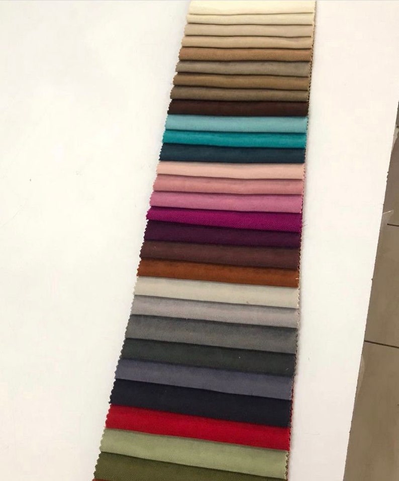 May include: A collection of fabric swatches in various colors, including beige, brown, teal, pink, purple, maroon, orange, gray, dark gray, navy blue, red, and green. The swatches are arranged vertically in a row.