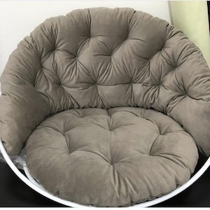 May include: A round, gray, tufted cushion chair with a white metal frame. The chair is designed for indoor use and has a comfortable, padded seat.