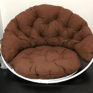 May include: A brown padded chair with a white metal frame. The chair has a round base and a comfortable, tufted cushion.