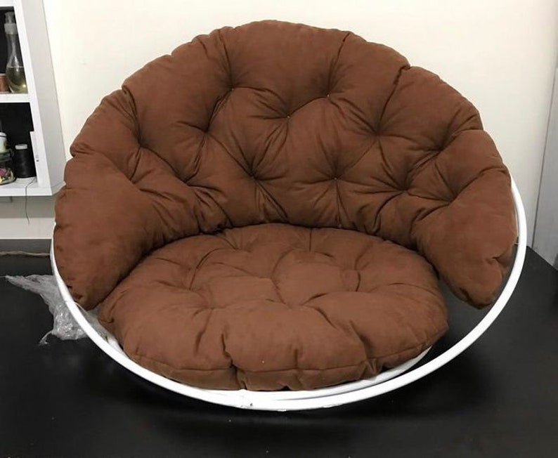 May include: A brown padded chair with a white metal frame. The chair has a round base and a comfortable, tufted cushion.