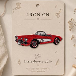 May include: An embroidered iron-on patch featuring a red vintage convertible sports car with white side detailing, black tires, and a black interior. The patch is mounted on a beige display card labeled IRON ON and little dove studio.