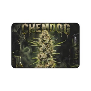 May include: A rectangular desk mat featuring a central cannabis flower bud against a dark, smoky background. The word CHEMDOG is printed in large, metallic, dripping block letters at the top. A glass beaker is visible on the left side.