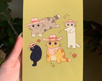 May include: Four cats wearing pink cowboy hats on a yellow background. One cat is gray and white, one is white, one is orange and white, and one is black. The cats are all looking at the viewer.