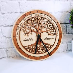 Puede incluir: Un reloj de madera con diseño de árbol y el texto "5 anos, 300 meses, 1304 semanes, 9132 dias! E o melhor ainda está por vir!" El reloj tiene los nombres "Anabela" y "Adriano" inscritos.