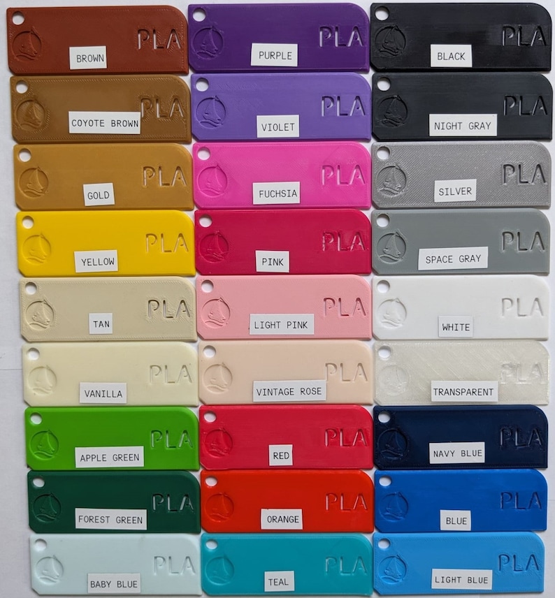 May include: A color chart of 18 different PLA filament colors for 3D printing. The colors include brown, purple, black, coyote brown, violet, night gray, gold, fuchsia, silver, yellow, pink, space gray, tan, light pink, white, vanilla, vintage rose, transparent, apple green, red, navy blue, forest green, orange, blue, baby blue, teal, and light blue.