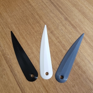 May include: Three plastic tools, one black, one white, and one grey, with a pointed tip and a hole at the end.