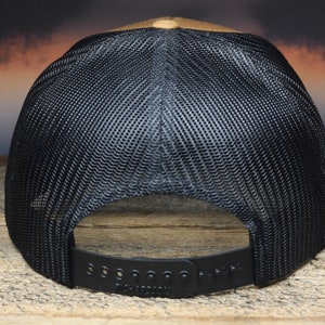 May include: A brown and black baseball cap with a black mesh back. The cap has a black adjustable strap with the word "Richardson" printed on it.