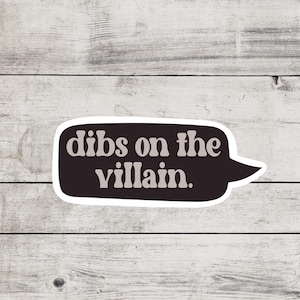 May include: A black and white speech bubble sticker with the text "Dibs on the villain." in a retro font.