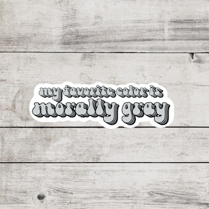 May include: A sticker with the text "my favorite color is morally gray" in a retro, layered, gray font.