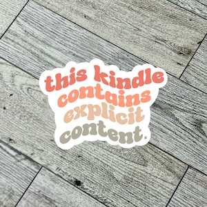 May include: A sticker with the text "this kindle contains explicit content." The text is in a rainbow gradient of pink, orange, and brown.