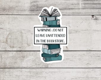 Op de afbeelding: Een sticker met een stapel boeken en de tekst "WAARSCHUWING: NIET ONBEWAAKT ACHTERLATEN IN DE BOEKENWINKEL."
