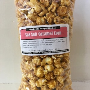 May include: A clear plastic bag filled with caramel corn with sea salt. The bag has a label that reads "Nashville Fudge Kitchen" and "Sea Salt Caramel Corn". The label also includes the ingredients and the text "Old Fashioned Since 1983."