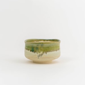 May include: A green and white ceramic teacup with a textured glaze.