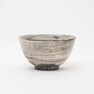 May include: A ceramic bowl with a textured, swirled design in shades of white, gray, and black. The bowl has a rounded shape with a slightly flared rim and a dark, textured base. The interior shows a similar pattern.