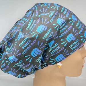 May include: A black scrub hat with a blue and purple print that says "Throat Punch Kinda Day". The hat has a drawstring and a small ice cream charm.