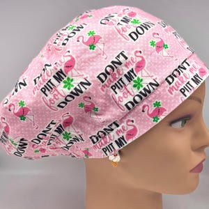 May include: Pink surgical scrub hat with a white polka dot pattern and pink flamingos. The hat has the text "Don't make me put my foot down" repeated on it.