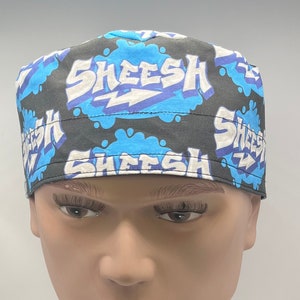 May include: A black and blue patterned cap with the word "SKEESH" in white and blue bubble letters. The cap has a lightning bolt graphic and is made of fabric.