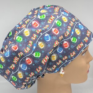 Puede incluir: Un gorro de quirófano azul con un patrón de luces navideñas y las palabras "FEN TA NYL FA LA LA LA LA" repetidas. Las luces son rojas, verdes, amarillas y azules.