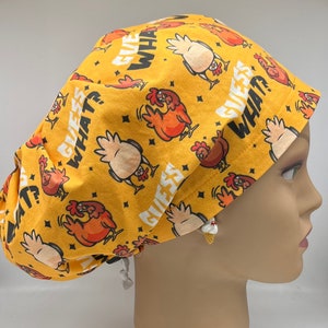 Puede incluir:  gorro de quirófano amarillo con un patrón repetido de pollos y el texto "Adivina qué?" en blanco.