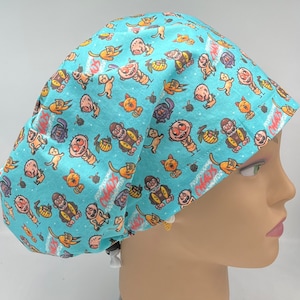 May include: A light blue scrub hat with a colorful pattern of cartoon characters and the text "Professional Crazy Cat Lady" repeated throughout.