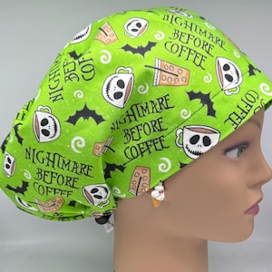 May include: A bright lime green scrub cap featuring a repeating pattern of white skull-faced coffee mugs, black bats, and coffee cups. The text "NIGHTMARE BEFORE COFFEE" is printed in black lettering throughout the fabric. The cap has an adjustable toggle.