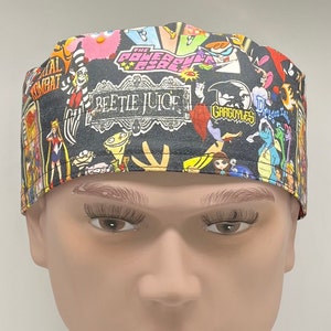 May include: A black scrub hat with a colorful cartoon print featuring characters from popular shows like "The Powerpuff Girls", "Beetlejuice", "Gargoyles", and "Dragon Tales".