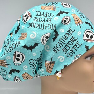 Puede incluir: Un gorro quirúrgico azul claro con un patrón repetido de tazas de café estilo Jack Skellington, murciélagos y la frase "Nightmare Before Coffee". Diseñado para profesionales de la salud.