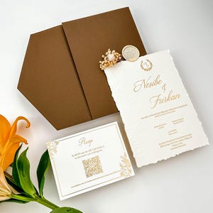 May include: A wedding invitation suite with a brown envelope, a textured white invitation with gold lettering, and an RSVP card. The invitation includes the names "Nesibe & Furkan" and floral accents.