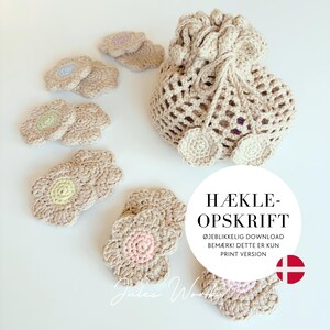 May include: A beige crocheted drawstring pouch with matching flower-shaped coasters in various pastel centres. A white circular graphic overlay features the text HÆKLE-OPSKRIFT, ØJEBLIKKELIG DOWNLOAD, BEMÆRK! DETTE ER KUN PRINT VERSION, and a small Danish flag icon.