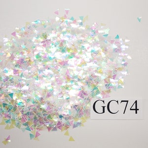 May include: A pile of iridescent holographic triangle glitter with a white background and the text "GC74" in black.