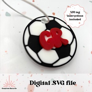 May include: A white and black soccer ball with the letters "CR" in red on top. The soccer ball is attached to a silver string. The text "NFC tag instructions included" is in a pink circle in the upper right corner of the image.
