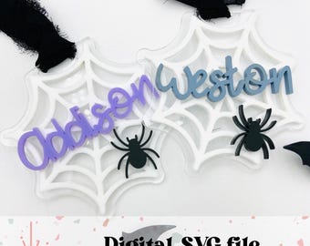 Può includere: Due ornamenti a forma di ragnatela in acrilico bianco con i nomi Addison e Weston in lettere viola e blu. Ogni ornamento ha un ragno nero al centro.