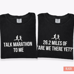 May include: Two black t-shirts. One features the text "TALK MARATHON TO ME" and a running figure graphic. The other says "26.2 MILES OF 'ARE WE THERE YET?'" with a similar graphic. Both have a Comfort Colors tag.