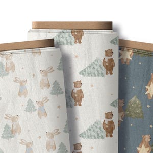 May include: Three rolls of fabric with winter-themed patterns. One roll features rabbits and Christmas trees, another has bears and trees, and the third has bears holding stars. The fabric has a light color palette.