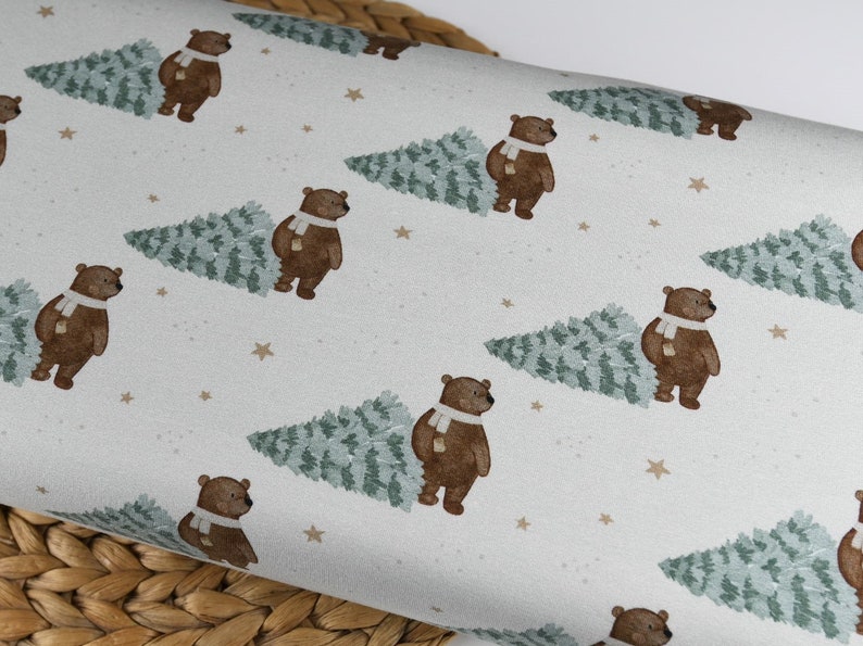 May include: A repeating pattern on a white background features brown bears wearing white scarves, each next to a green Christmas tree. Small tan stars are scattered across the surface, creating a festive, wintery design.