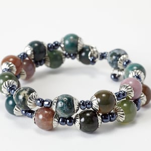 May include: A multi-strand bracelet with green, brown, and pink agate beads separated by dark blue beads. The beads are accented with silver caps.