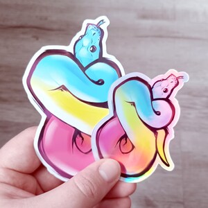 May include: Two iridescent rainbow colored snake stickers. The top snake is blue and yellow, the bottom snake is pink and yellow. Both snakes are curled up in a circle.
