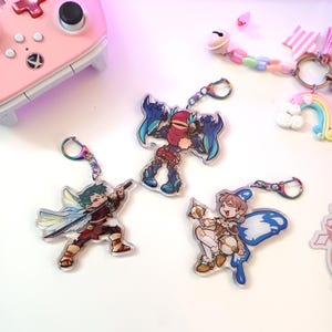 May include: Three colorful anime character keychains with blue, red, and yellow accents. The keychains are made of clear acrylic and feature detailed illustrations of the characters.