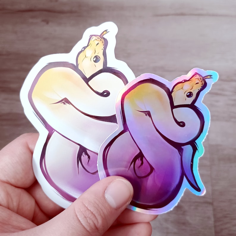 May include: Two iridescent vinyl stickers featuring a curled up snake with a yellow and purple color scheme.